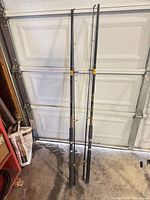 Two full length fishing rods leaning against garage door