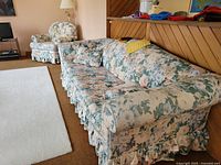 Sofa and matching armchair showing floral upholstery and ruffled skirts