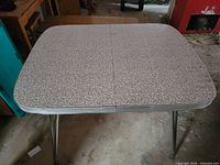 Top view of rectangular metal kitchen table showing laminate surface and chrome legs
