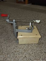 Manual apple peeler-corer on wooden base with red crank handle