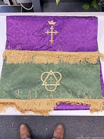 Runner folded to show both purple and green sides with gold fringe and emblems