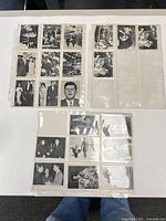 Three binder pages holding vintage JFK photo cards on white table