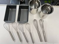 Group shot of all items: 4 whisks, 2 loaf pans, 2 stainless steel canisters