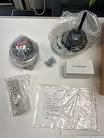 All components laid out: camera, mount, adapter box, remote, screws, manual