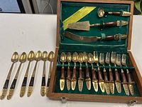 Open wooden box showing full flatware set and extra spoons