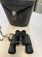 Binoculars and black hard leather case on table