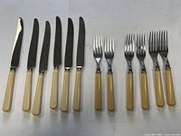 Six knives and six forks laid out side-by-side showing full set