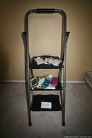 Full view of Cosco 3-step ladder holding phone accessories