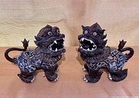 Front view of both glazed ceramic foo lions, mouths open, showing overall design and condition.