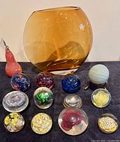 Group shot of amber vase and twelve paperweights