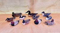 Group shot of eleven small waterfowl decoys arranged on surface