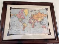 Framed world map hung on wall showing frame, mat and full artwork