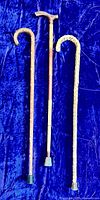 Three canes laid out on blue fabric, full length view