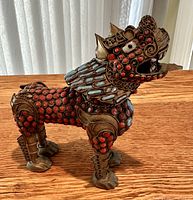 Side profile of inlaid brass guard lion showing coral and blue bead detail