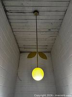 Pendant lamp assembled and hanging, showing gold leaves and illuminated white globe