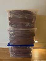 Three clear bins stacked, each containing packaged rust robes