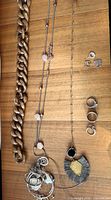 Overview of entire lot showing acrylic chain necklace, two long costume necklaces with pink beads, grey fringe pendant necklace, four sterling rings, pair of cubic-zirconia studs and tangled sterling pieces