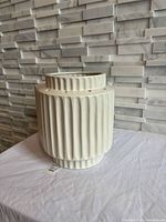 Front and side view of one ceramic sconce showing ribbed design and top opening