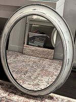 Front view of oval mirror showing frame style and white-washed finish