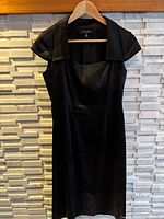 Front view of black faux silk dress on hanger