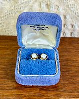 Open blue velvet box showing both gold opal stud earrings