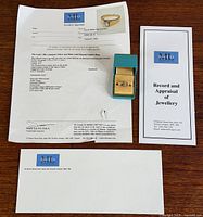 Ring with appraisal, box and envelope displayed on table