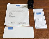 Layout showing ring in box, appraisal document, brochure and envelope
