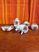 group shot of five crested porcelain pieces