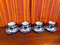 Full set of four blue and white porcelain cups with matching saucers displayed side by side