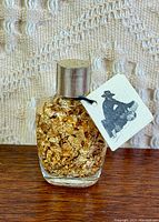 Front view of unopened bottle filled with gold flakes, tag attached