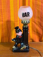 Full view of lamp showing figure, post, globe, cord