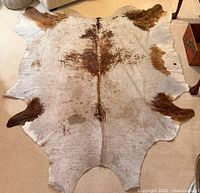 Full view of faux cowhide rug laid flat