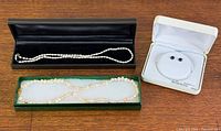 Three jewellery pieces in presentation boxes: two necklaces and earrings
