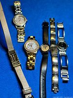 Overview of all five watches and spare strap on blue background
