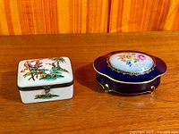 Both porcelain dresser boxes side by side on table