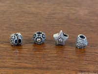 All four Pandora silver charms aligned on wood surface