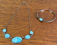 Necklace and bangle laid flat showing stones and metal