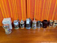 Row of nine assorted beer steins and tankards on table