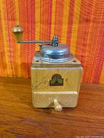 Front view showing wood body, metal lid, crank, decal