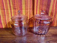 Front view of both pink Depression glass cookie jars with lids