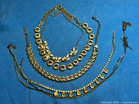 Overview of four gold-tone necklaces on blue fabric