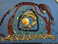 All eight necklaces laid out on blue cloth