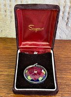 Pendant in open presentation box showing pansy design