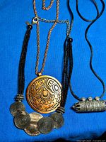 All three necklaces laid on blue background showing overall designs