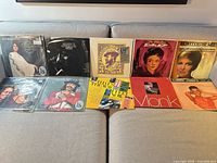 Overall shot of 10 vintage vocal and jazz LPs laid out in two rows on sofa; visible artists include Peggy Lee, Eartha Kitt, Thelonious Monk and others