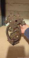 Front view of cast-iron door knocker showing ornate design