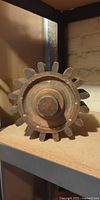 frontal view of antique wooden gear showing teeth, hub, and patina