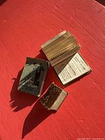 Three miniature books shown: green Dance Lesson booklet, open small book, diminutive brown leather-bound volume for scale against hand and ruler