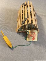 Angled view of miniature wooden lobster trap with buoy and tag visible