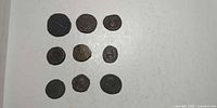 All nine coins arranged in three rows on white surface